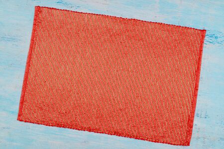 Red golden piece of cloth. Shiny napkin on a blue surface.の写真素材