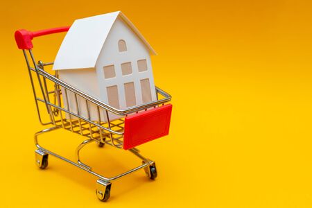 Little white paper house in trolley. Selling real estate in store. の写真素材