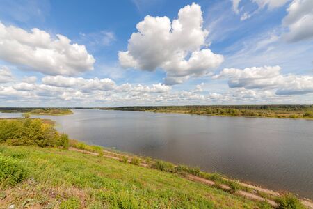 Wide river. Summer sunny day. White clouds on a blue sky.