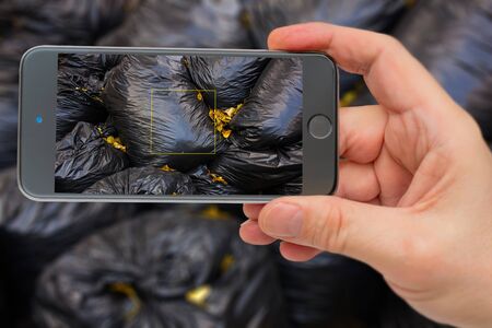 Garbage bags in smartphone screen. Garbage collection. Black bags of garbage.の写真素材