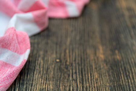 Red and white kitchen towel lies on wooden table. Texture of painted wood. Textured fabric folds.の写真素材