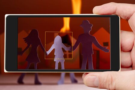 Fire on smartphone screen. Family at burning house.