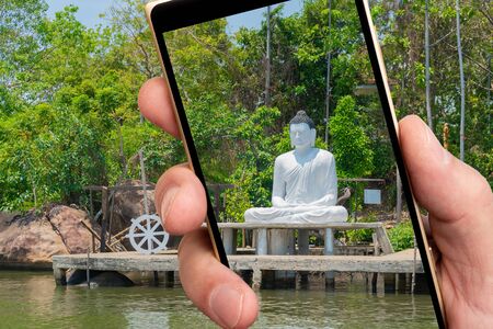 Buddha statue on smartphone screen. Buddha image made of white stone.