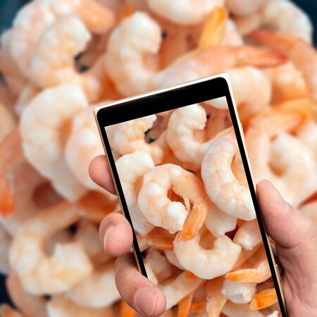 Frozen shrimp on smartphone screen. Natural seafood.の写真素材