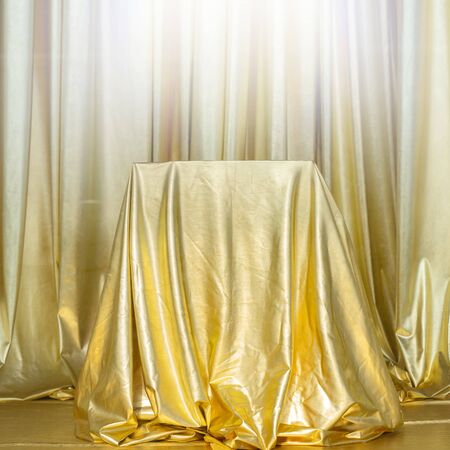 Stand draped in gold fabric. Abstract golden background.の写真素材