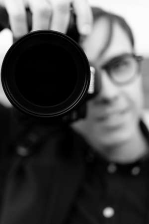 Young white man holding a camera. Reportage photography on the street. Selective focus.の写真素材