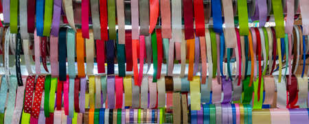 Rolls of multicolored silk ribbons in a shop window. Accessories for packing and decorating gifts.
