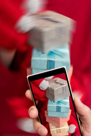 Christmas gift box on the smartphone screen. Festive composition. Red background.の写真素材