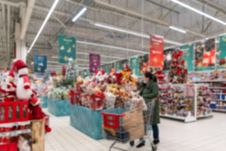 Blurred Christmas supermarket. Sale of festive Christmas accessories and trees in a retail store. Blurred background in the store. Selective focus.の写真素材