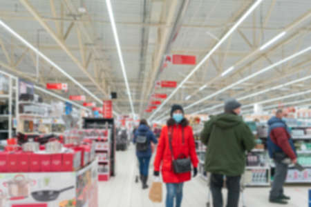 Blurred supermarket. Selling goods in a retail store. Blurred background of consumers in medical masks in a store.の写真素材