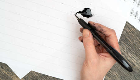 Calligraphy training. Fountain pen in ink-stained hands.の写真素材