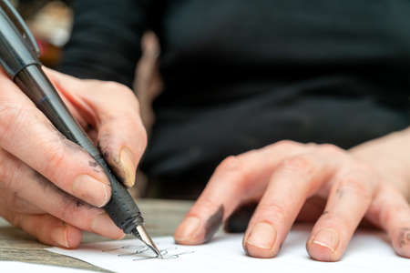 Calligraphy training. Fountain pen in ink-stained hands.の写真素材