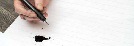 Calligraphy training. Fountain pen in ink-stained hands.の写真素材