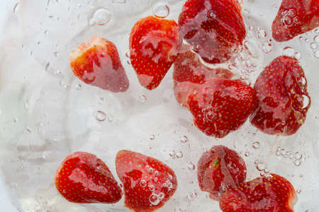 Ripe red strawberries are washed in water. A useful berry for farming.の写真素材