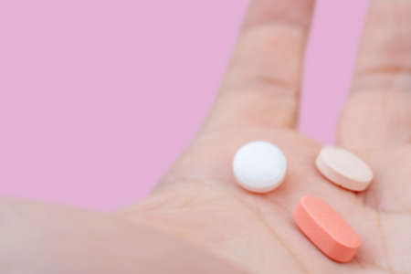 White and pink pills in the palm of your hand. Treatment with pills.の写真素材