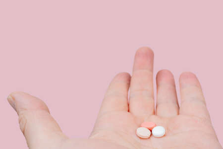 White and pink pills in the palm of your hand. Treatment with pills.の写真素材
