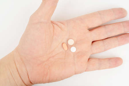 White and pink pills in the palm of your hand. Treatment with pills.の写真素材