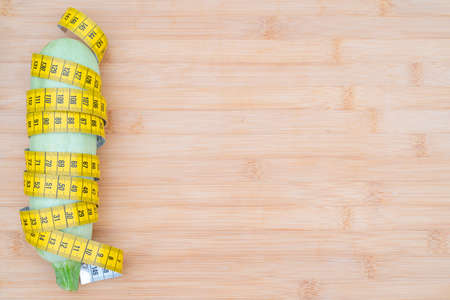 Yellow measuring tape and vegetables on a wooden cutting board. Healthy lifestyle diet.の写真素材