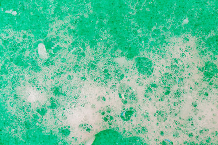 White soap suds on a green sponge. Cleanliness and disinfection of dishes.の写真素材