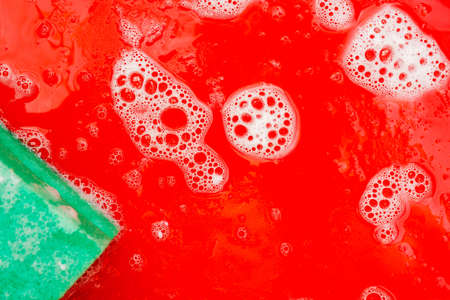 Disinfection of red plastic food tray in fast food. Washing the tray with a sponge and soap.の写真素材