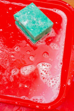 Disinfection of red plastic food tray in fast food. Washing the tray with a sponge and soap.の写真素材
