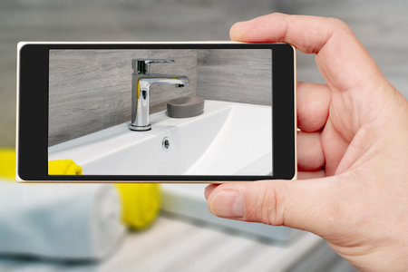 Water tap on smartphone screen. Water tap and sink in the bathroom. The interior of the living quarters.の写真素材