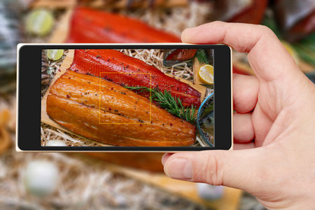 Smoked fish on smartphone screen. Selling seafood in a supermarket. Delicious delicacy fish for a festive table.の写真素材
