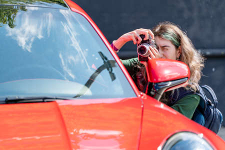 Moscow. Russia. August 13, 2021. Girl with a camera. Photoshoot with a red car.