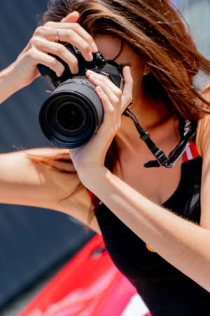 Moscow. Russia. August 13, 2021. Girl with a camera. Photoshoot with a red car.のeditorial素材