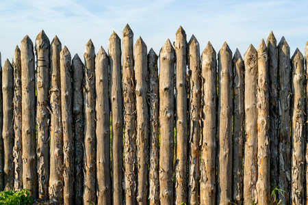 Wooden palisade made of logs. Log wooden fence. Sharp stakes in the ground.の写真素材