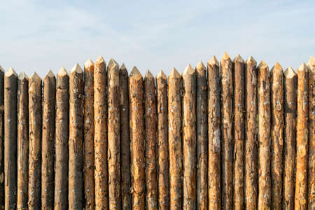 Wooden palisade made of logs. Log wooden fence. Sharp stakes in the ground.の写真素材