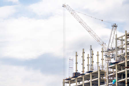 Construction cranes near the facade of a house under construction. modern building industry. Sale and rental of real estate.の写真素材