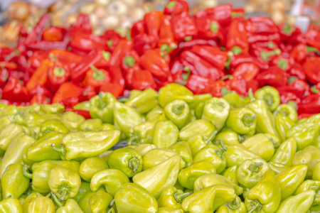 A bunch of green and red peppers are displayed in a marketの写真素材