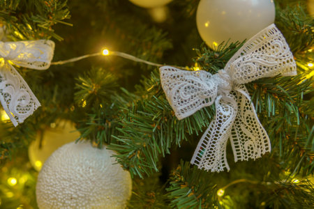 Shiny silver bow, New Year's toy, hanging on the branches of the Christmas tree. Festive Christmas background.の写真素材