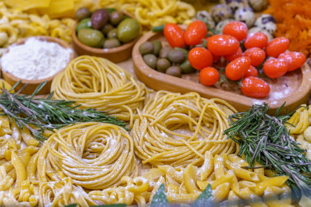 A table full of food including pasta, olives, tomatoes, and quail eggs. The table is set for a meal and the food looks deliciousの写真素材