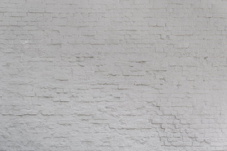 A wall made of white brick. The wall is very old and has many uneven surfaces.の写真素材