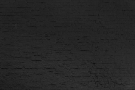 A wall made of black brick. The wall is very old and has many uneven surfaces.の写真素材