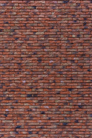 A brick wall with a brown and tan color. The wall is made of bricks. The bricks are arranged in a pattern.の写真素材