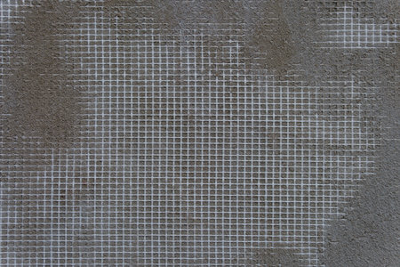 A gray wall with a white mesh pattern. The mesh is in the shape of squares.の写真素材