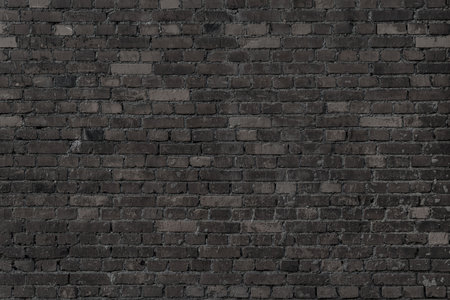 Black wall of black bricks - glowy room. Industrial building background.