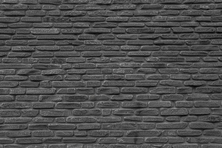 The black wall is made of uneven black stones. Abstract dramatic background.の写真素材
