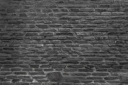 The black wall is made of uneven black stones. Abstract dramatic background.の写真素材