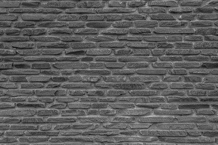 The black wall is made of uneven black stones. Abstract dramatic background.の写真素材