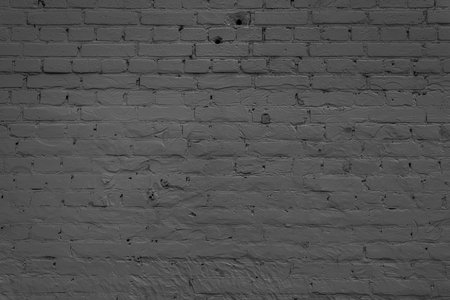 A black brick wall stands in the darkness. Atmospheric, dramatic, mysterious background.の写真素材