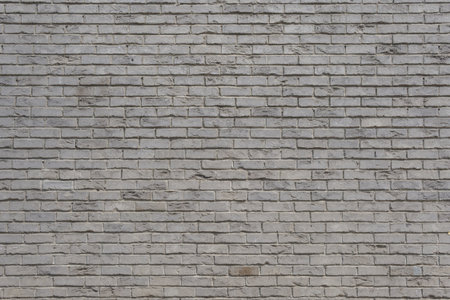 A textured white brick wall bears the marks of time and history urban. Its warm hue and rough...