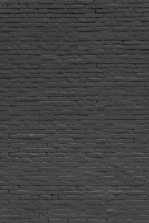 A textured black brick wall bears the marks of time and history urban. Its warm hue and rough surface evoke a sense of nostalgia, craftsmanship, and industrial charm.の写真素材