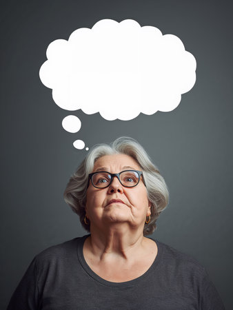 A sad elderly woman is lost in thought. Above her head is a blank thought bubble for text.の素材