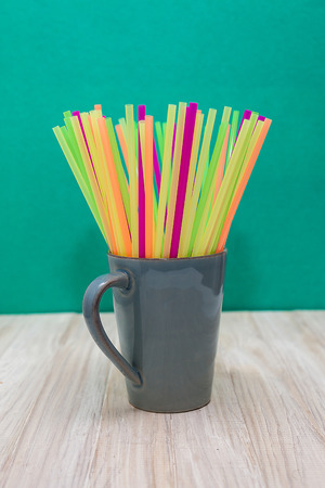 A Grey Ceramic Mug Filled With Plastic Straws of Several Colorsの写真素材