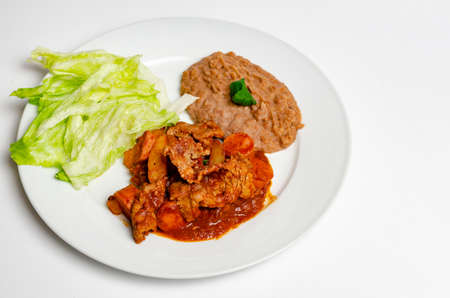 food plate consisting of meat and sausages in spicy sauce, with salad and beansの写真素材