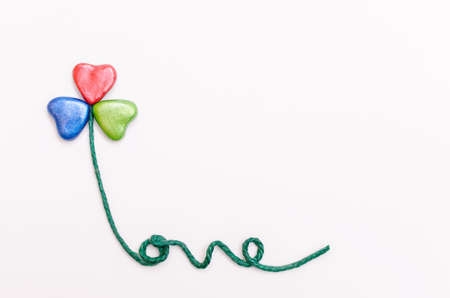 Clover-shaped flower with colorful hearts petals. The stem in the form of text.の写真素材